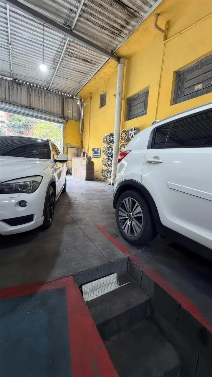 Salão da Oficina MSW, com paredes amarelas, rodas expostas e dois SUVs brancos estacionados